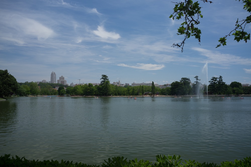 Het meer (lago) in het park Casa de Campo, met op de achtergrond de gebouwen van de stad, te Madrid